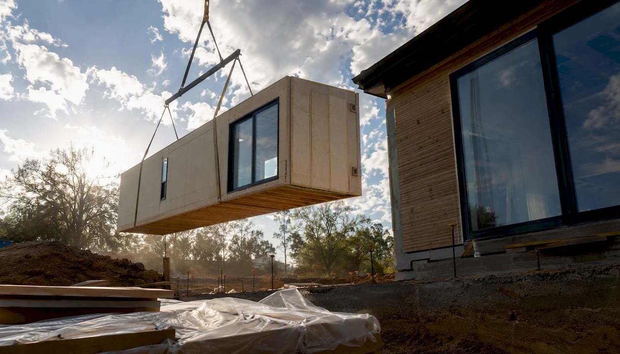 Crane lifting modular home panel on site